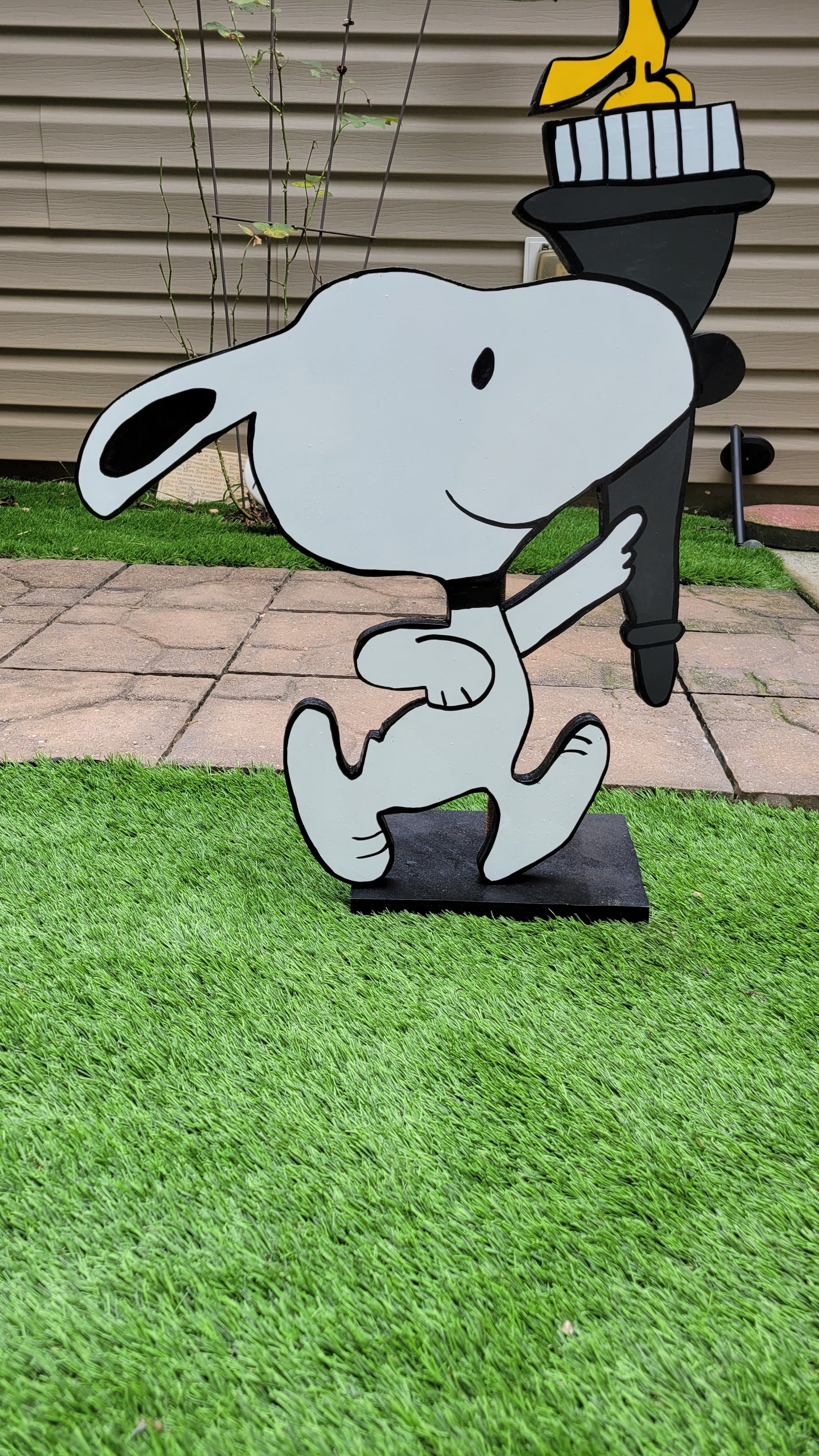 Snoopy carrying  Olympic torch. Yard art